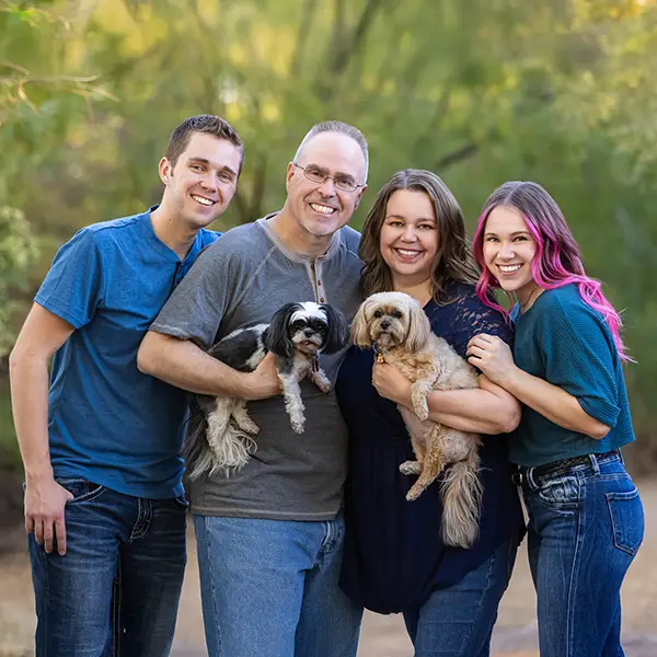 Smiling family of four with two small dogs during an outdoor photo session in Mesa, Arizona.