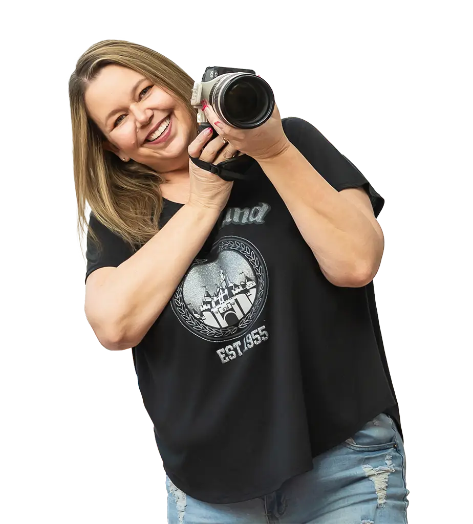 Michelle Robertson smiling and holding a camera while wearing a Disneyland shirt.
