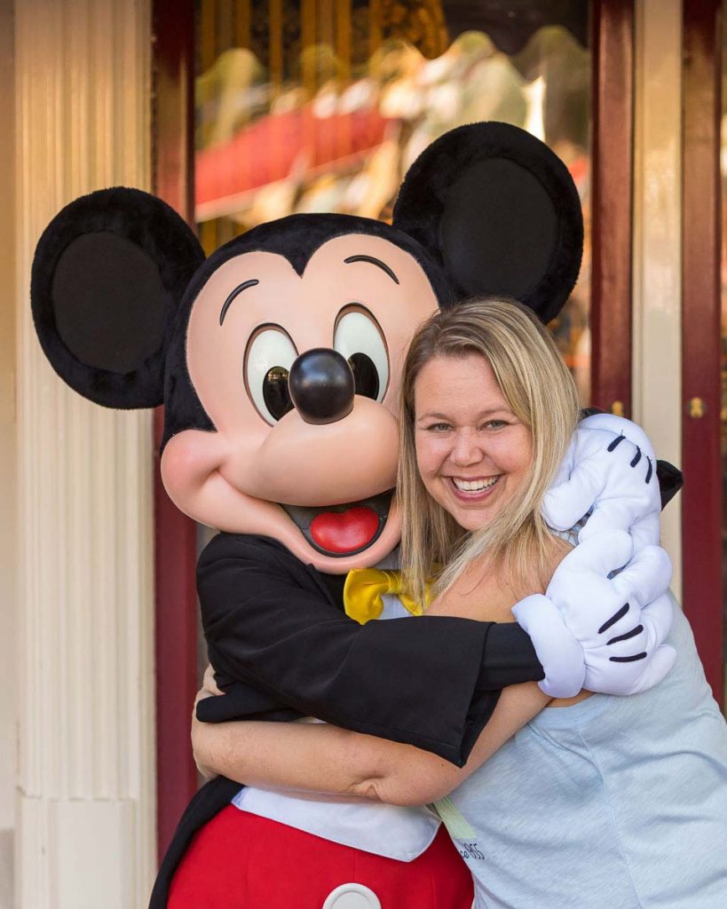 Michelle hugging Mickey Mouse and smiling during a Disneyland trip.