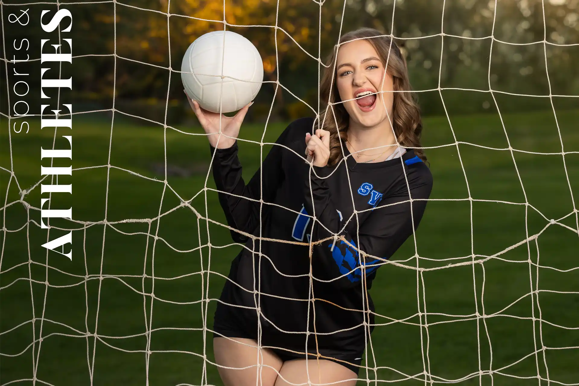 Senior girl in a volleyball uniform holding a volleyball and posing through the net in Chandler, Arizona.