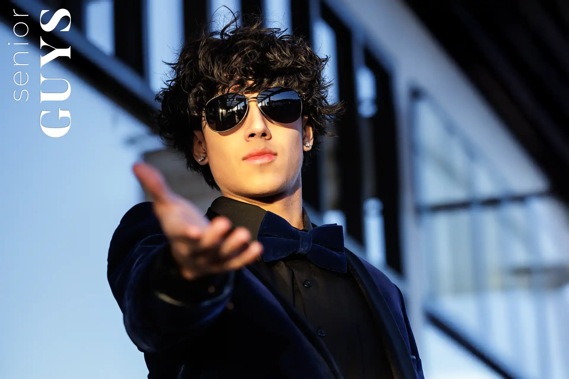 Senior guy in a dark suit and sunglasses posing during his senior photo session in Chandler, Arizona.