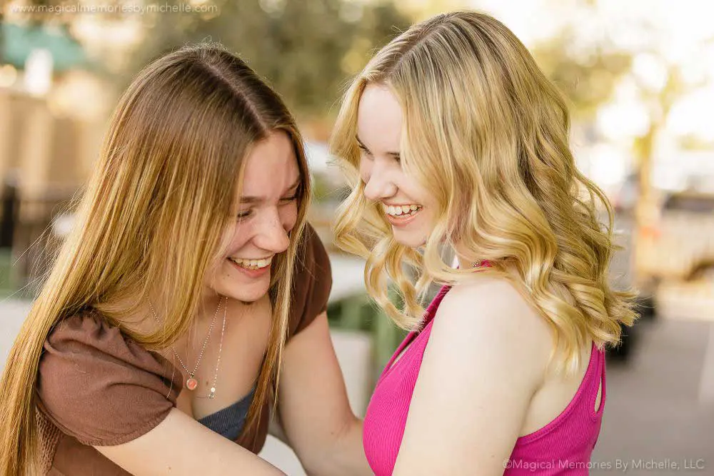 Two senior girls laughing together during a fun outdoor photo session in Chandler, Arizona.