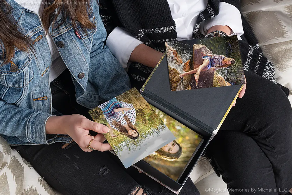 Hands holding printed boho senior pictures and custom album from Chandler photo session.