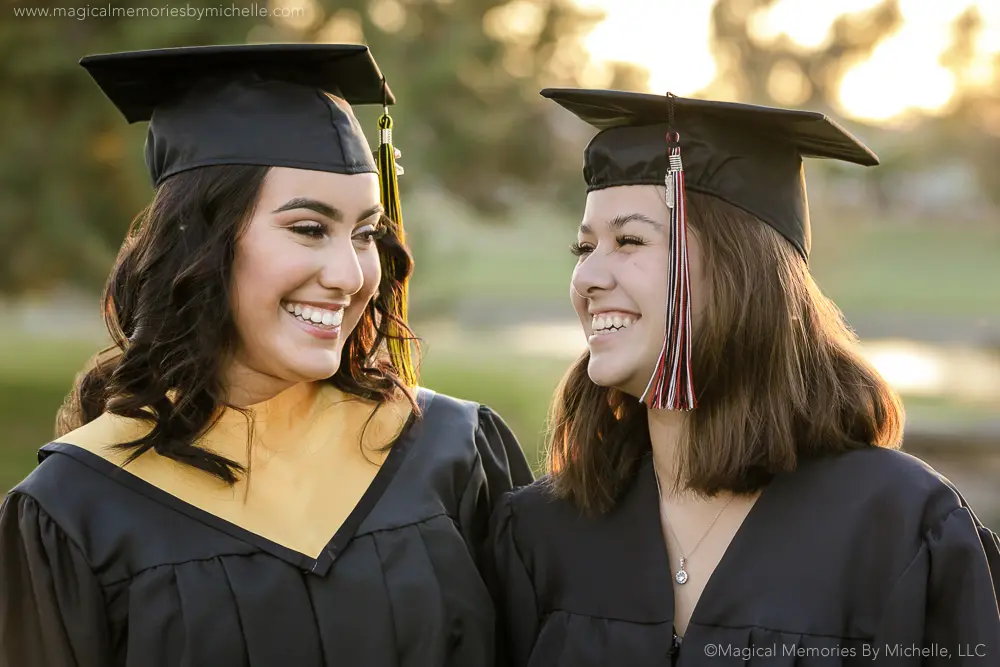 Two senior girls in cap and gown laughing at Veterans Oasis Park in Chandler Arizona.