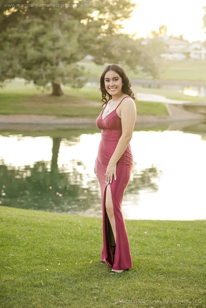 Senior girl in red prom dress standing by water in Chandler Arizona