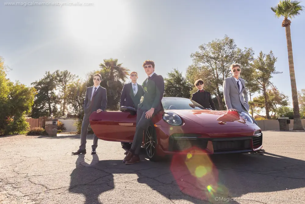 Arizona senior guys in prom suits posing with a red Porsche during a high school portrait session.