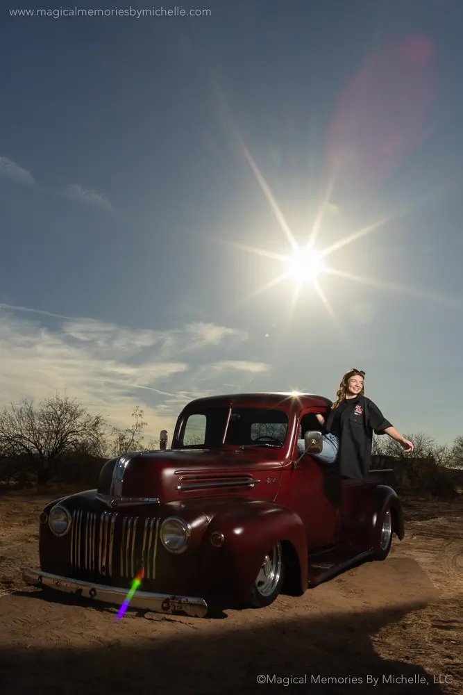 Senior girl poses in the Arizona desert with a vintage truck, capturing a rustic, sunset-themed car photoshoot.