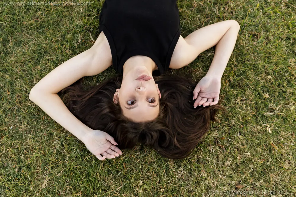 Teen girl lying on the grass with a natural, confident expression during her senior portrait session.