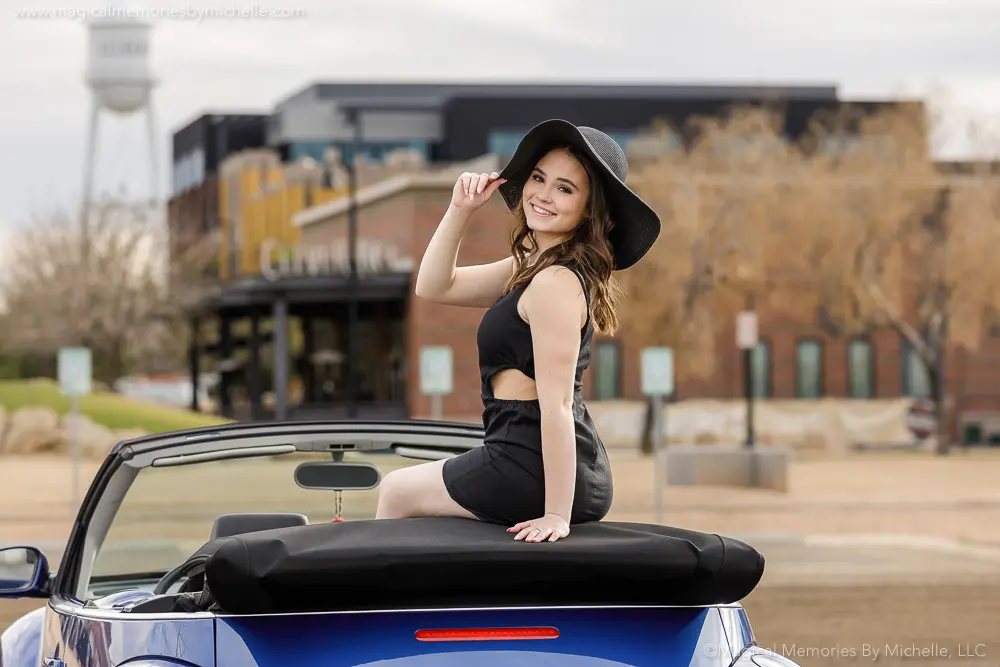 Fun senior portrait of a teen girl sitting on a blue convertible during her car-themed photo session in Gilbert, AZ.