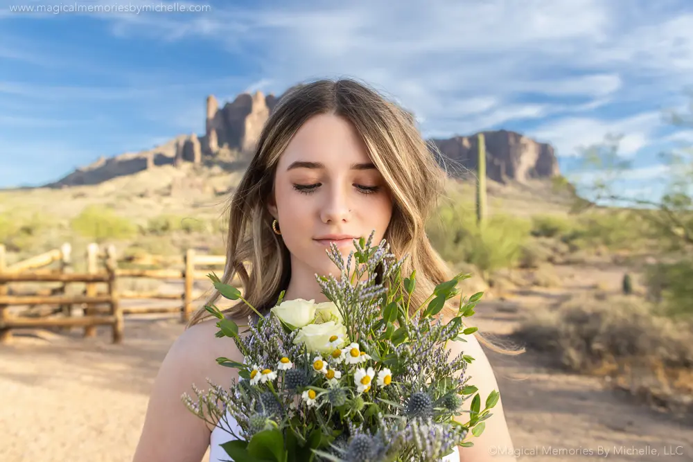 Senior girl holds a wildflower bouquet while standing in front of the Superstition Mountains in Mesa, Arizona.
