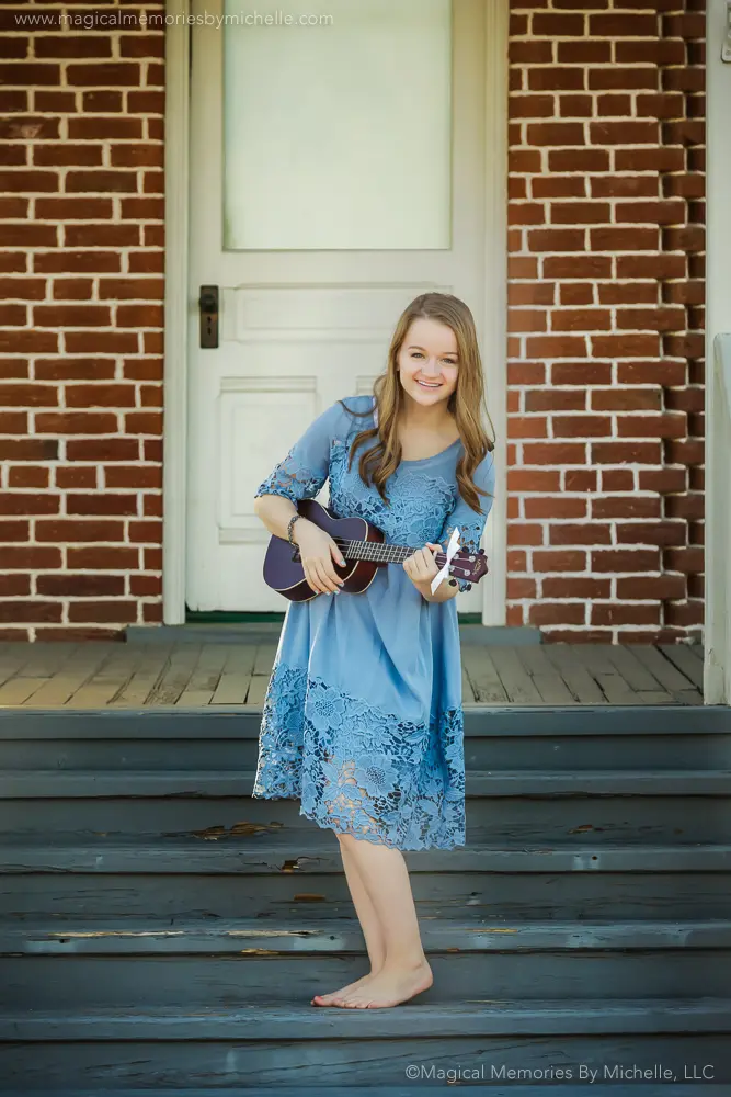 Barefoot senior girl smiling while playing her ukulele on vintage wooden steps in Downtown Mesa.